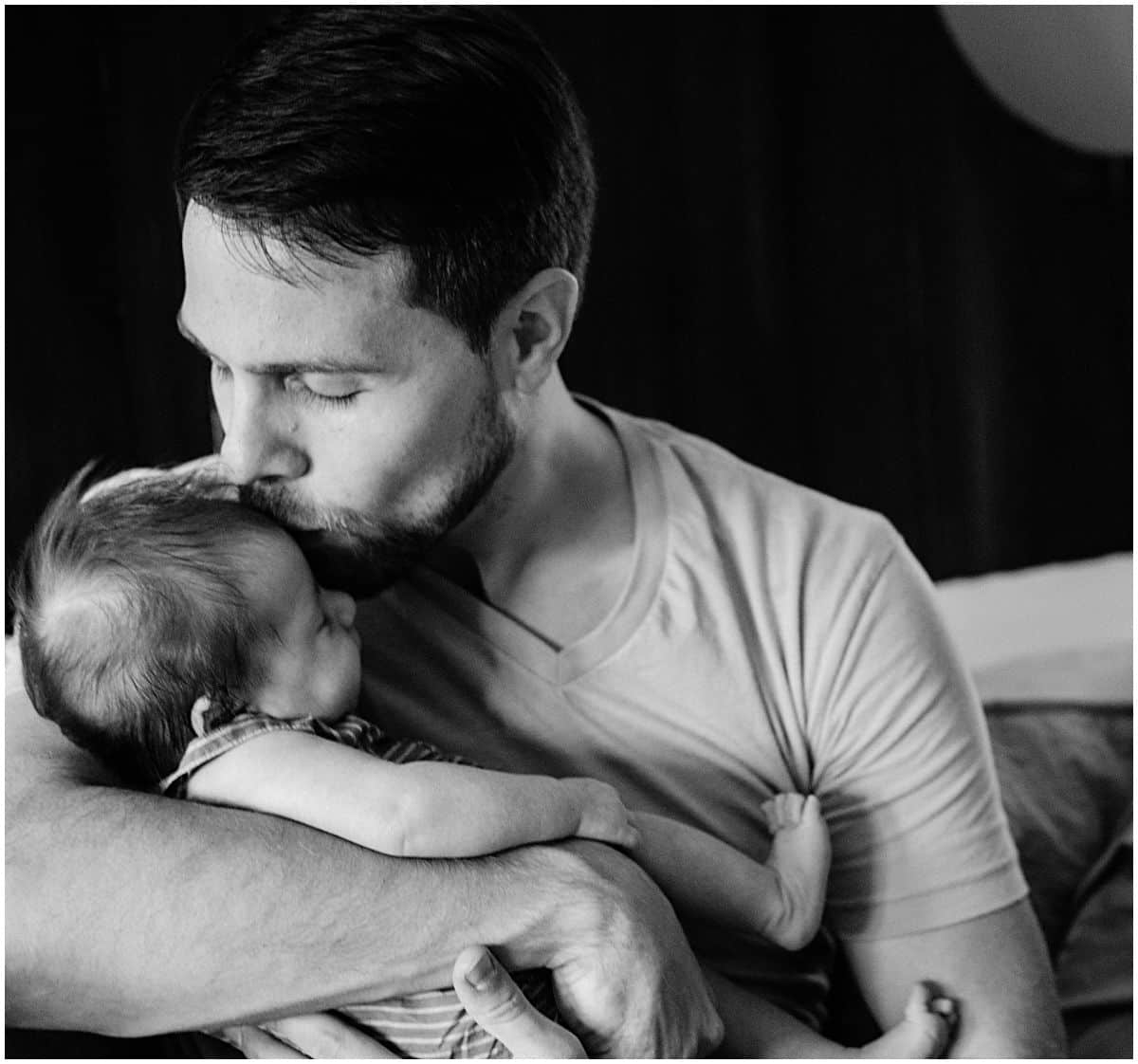 a father tenderly kissing his baby girl in newborn portrait by the best newborn photographer in NYC