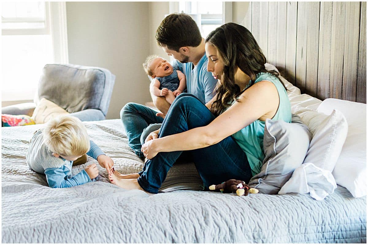 little boy playing with mom toes in family photos on bed in Montclair NJ