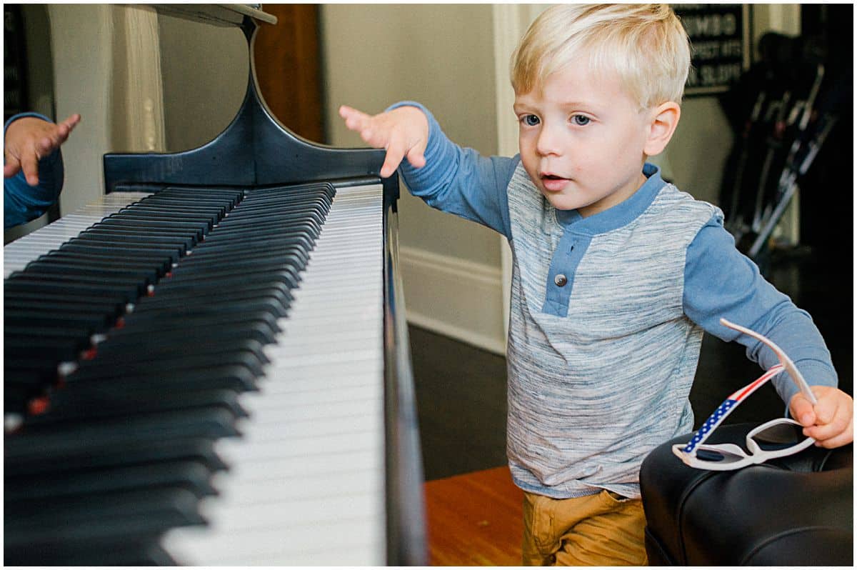 little blond boy playing piano at his home during family photo session in NJ