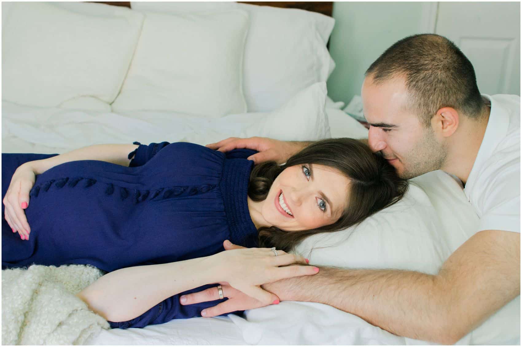 dad kissing his happy pregnant wife who holding her belly at maternity photoshoot
