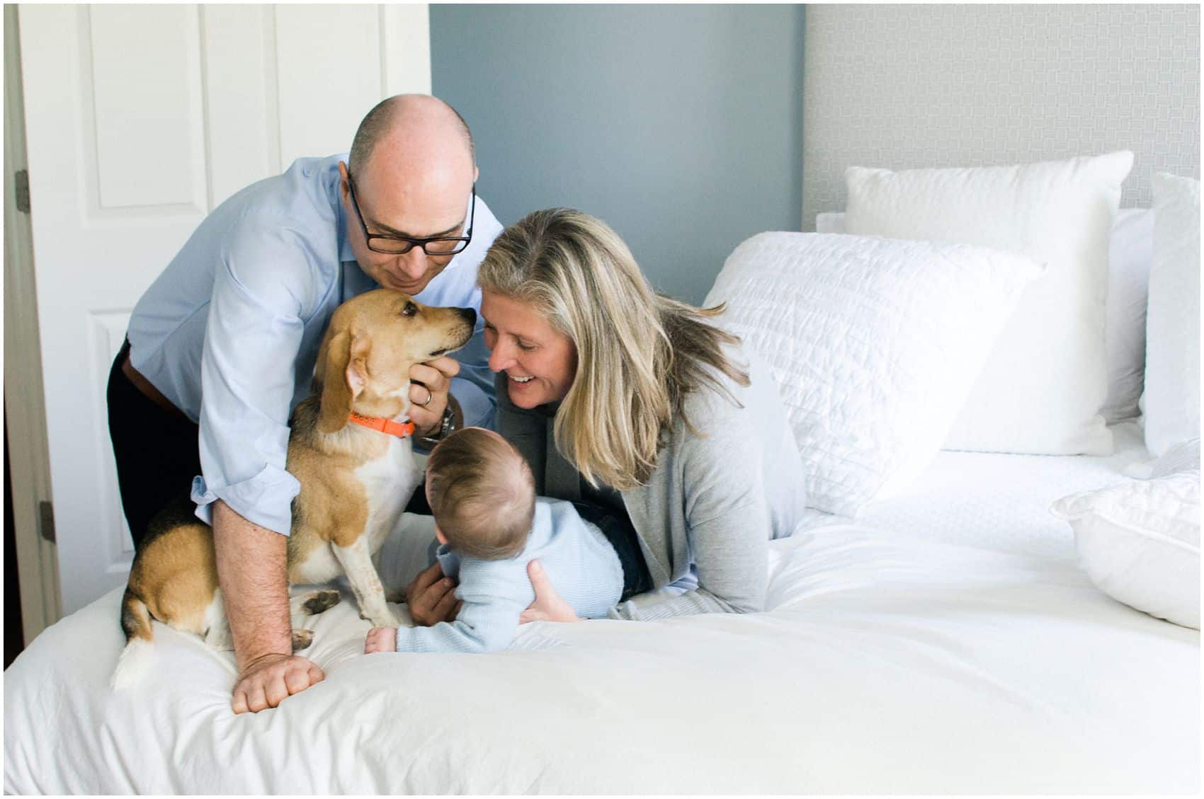 family portrait with the pet and the baby at home on the white bed