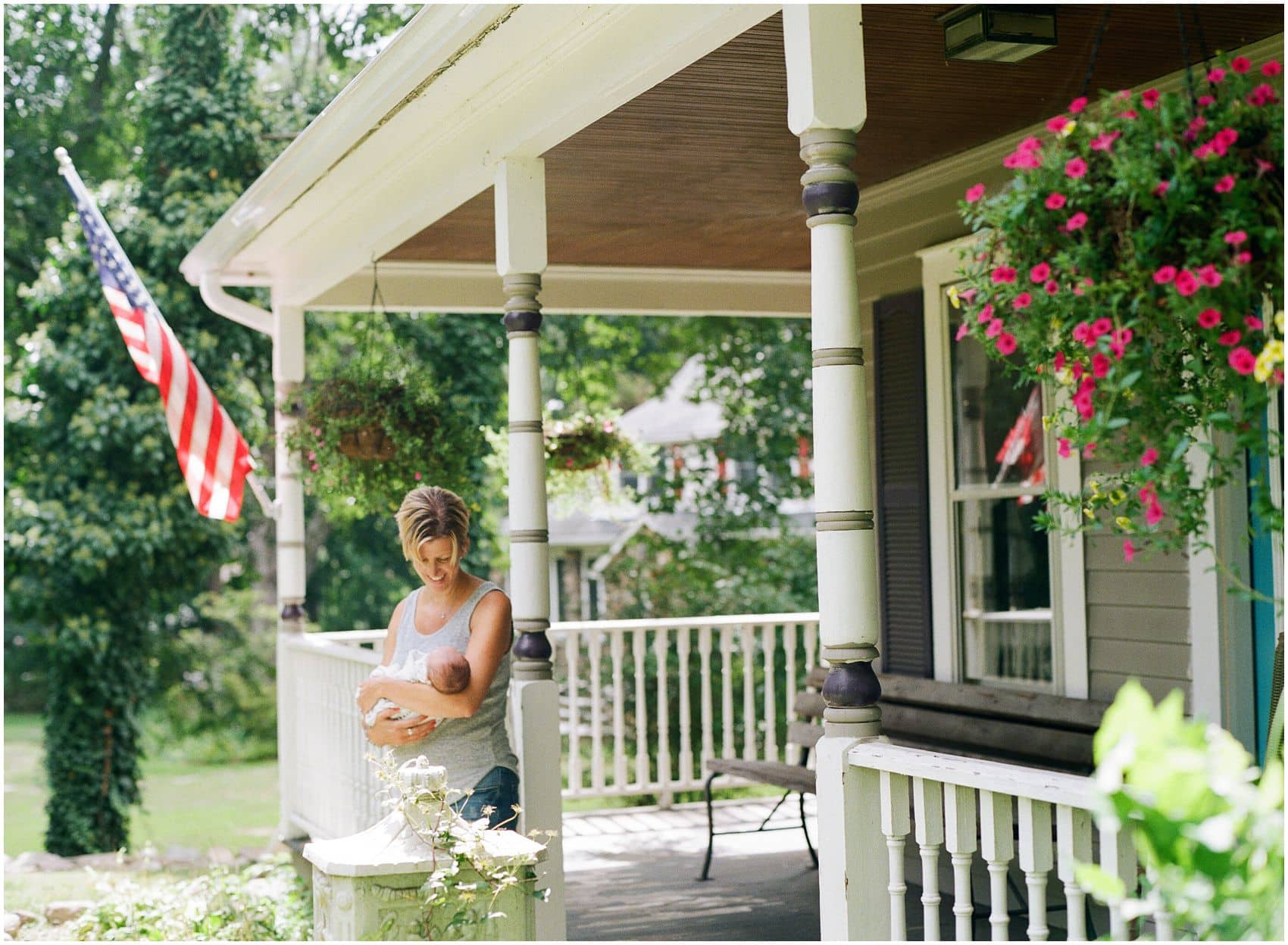 mom holding baby during newborn photo session outside by american flag