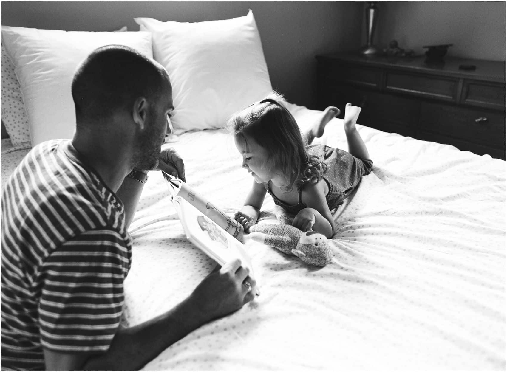 black and white portrait of a dad reading to his daughter 