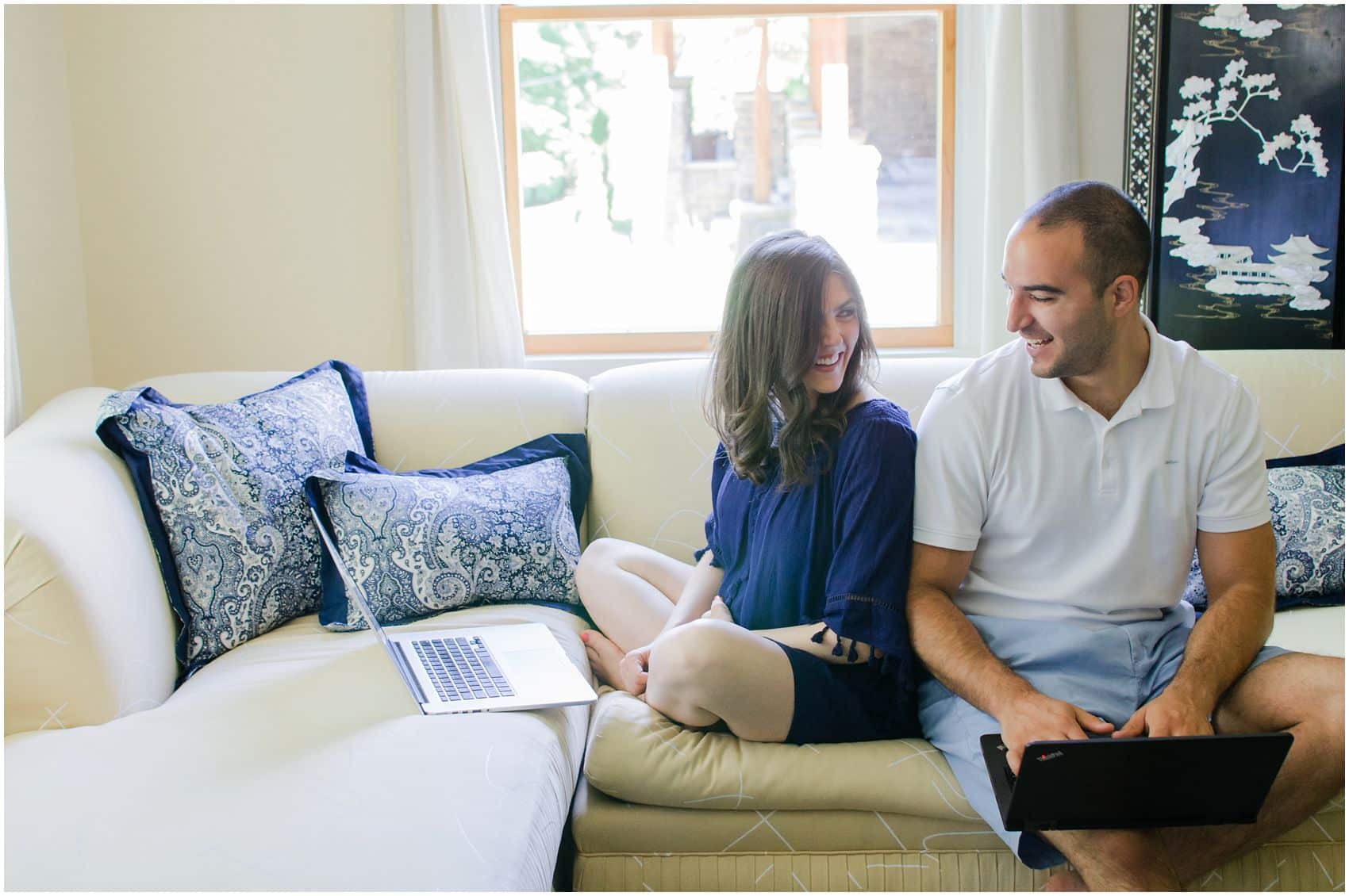 husband and wife smiling at each other while working on computers side by side in Manhattan NY