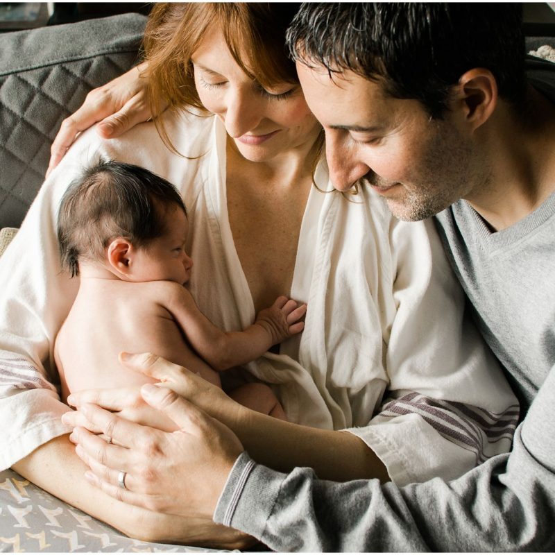 mom and dad snuggling with naked newborn baby in Chelsea NY