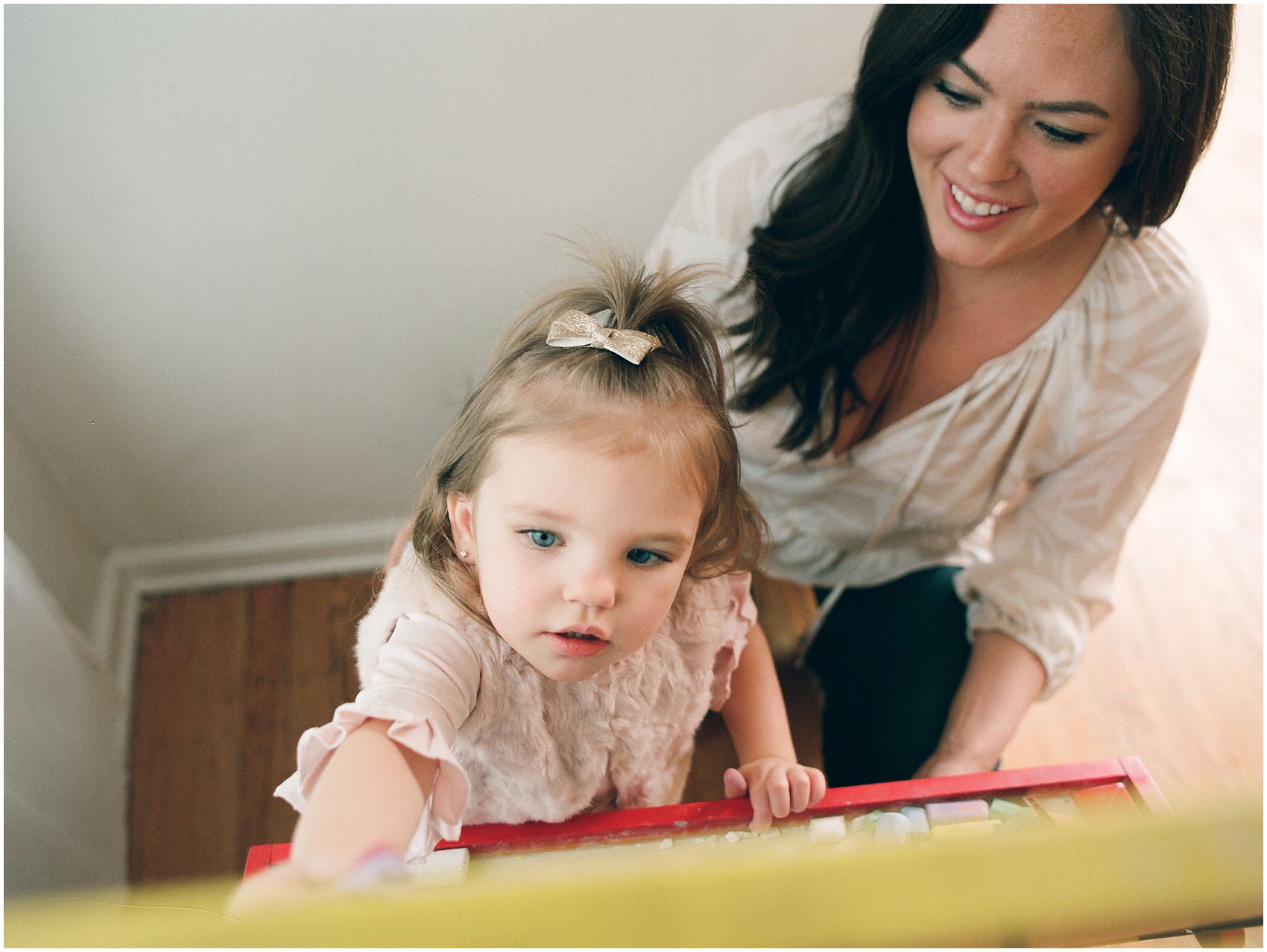 family photos in NJ with little girl coloring and drawing on the easel board with mom