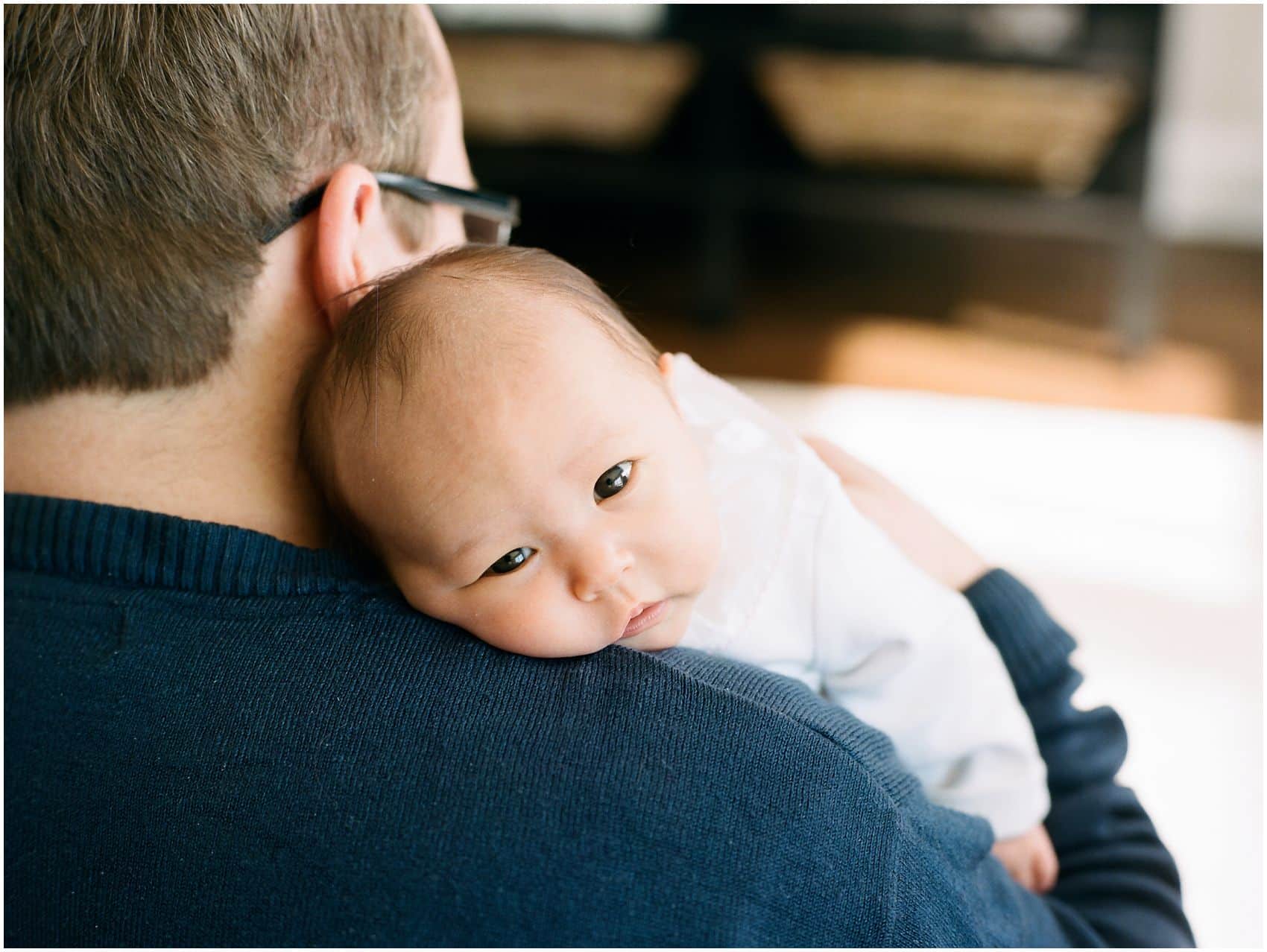 baby girl looks overlooks dad's shoulder during newborn photos in NYC