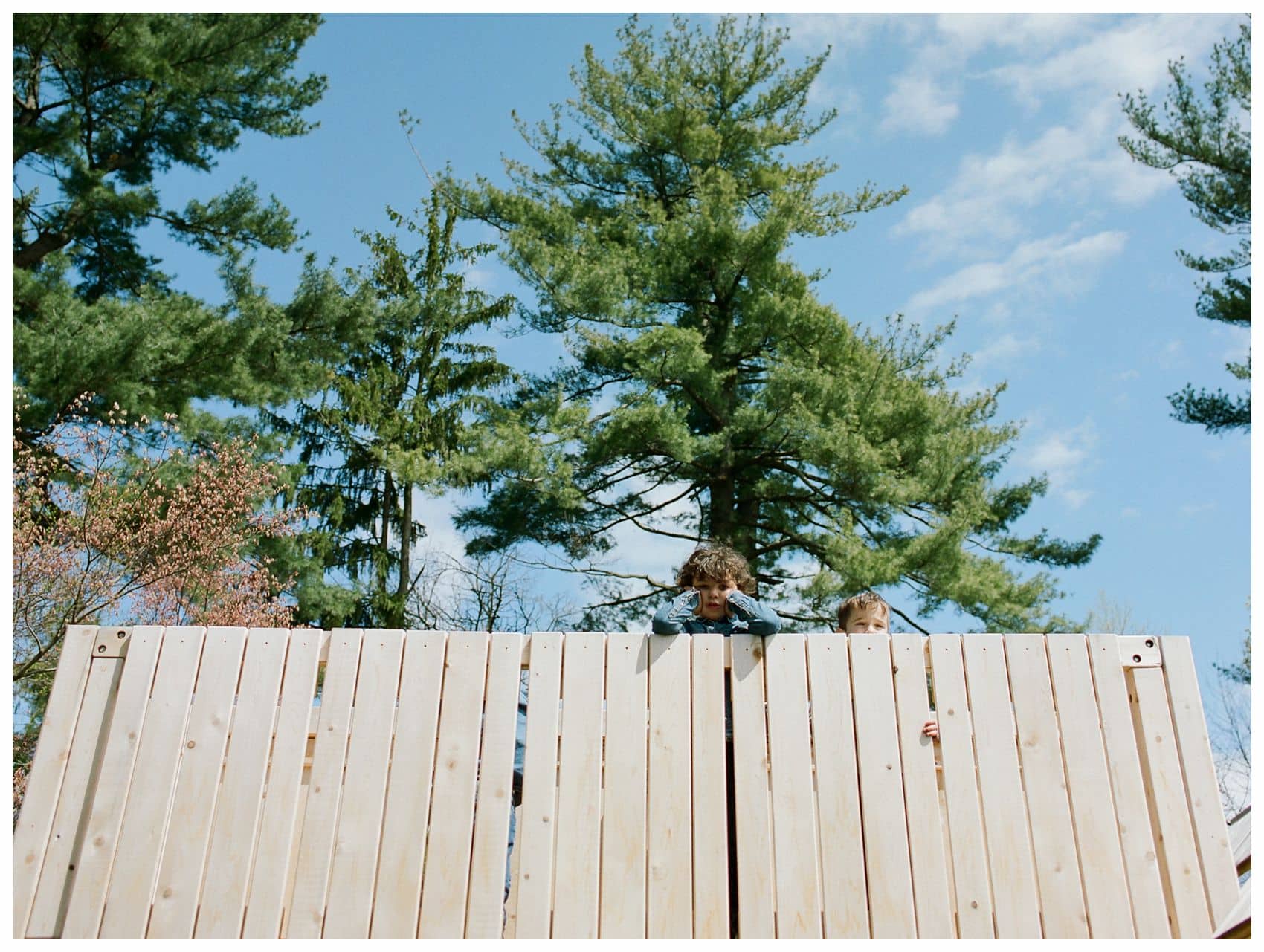 two boys looking over the playground fence in family photo in NJ