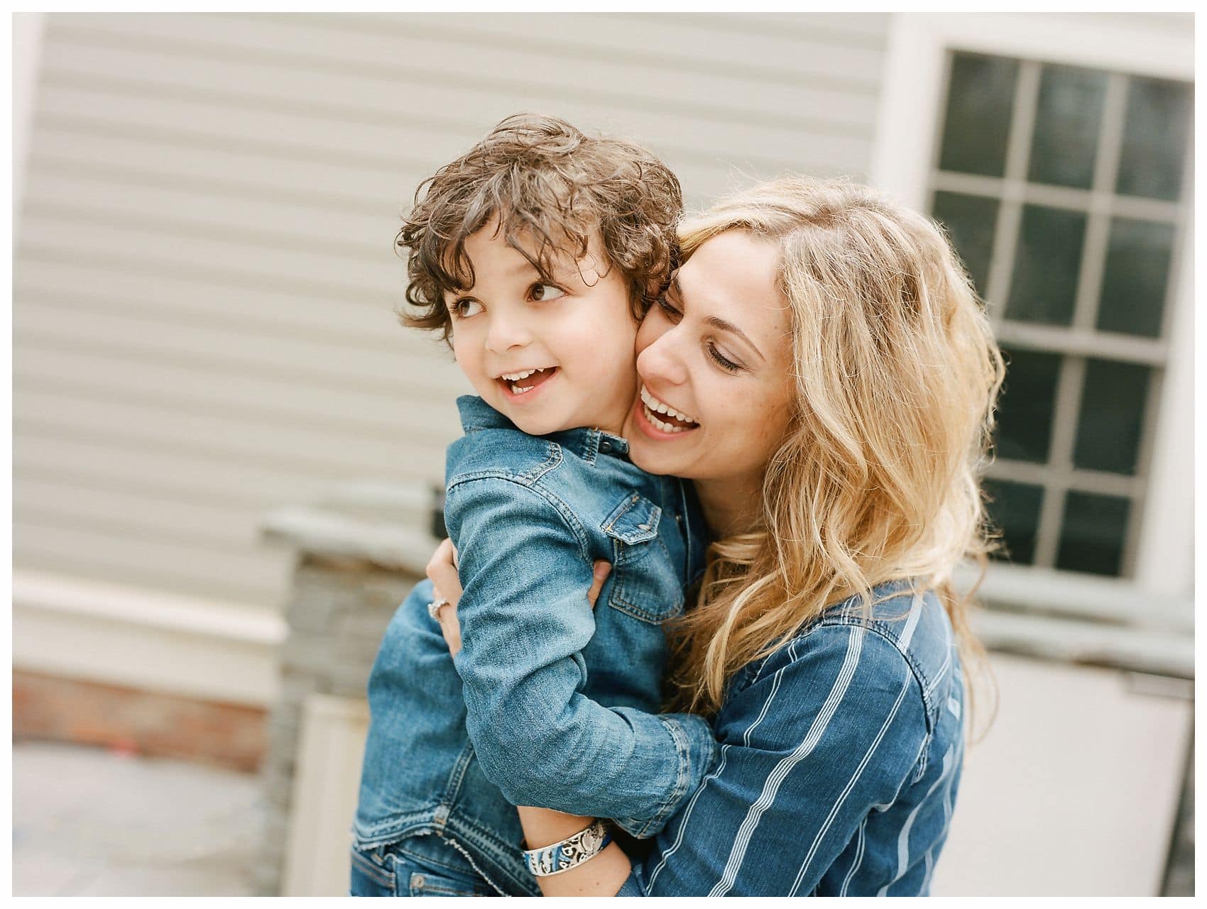 blond mom with beach wavy hair hugging and laughing with her son in a family photo in Montclair NJ