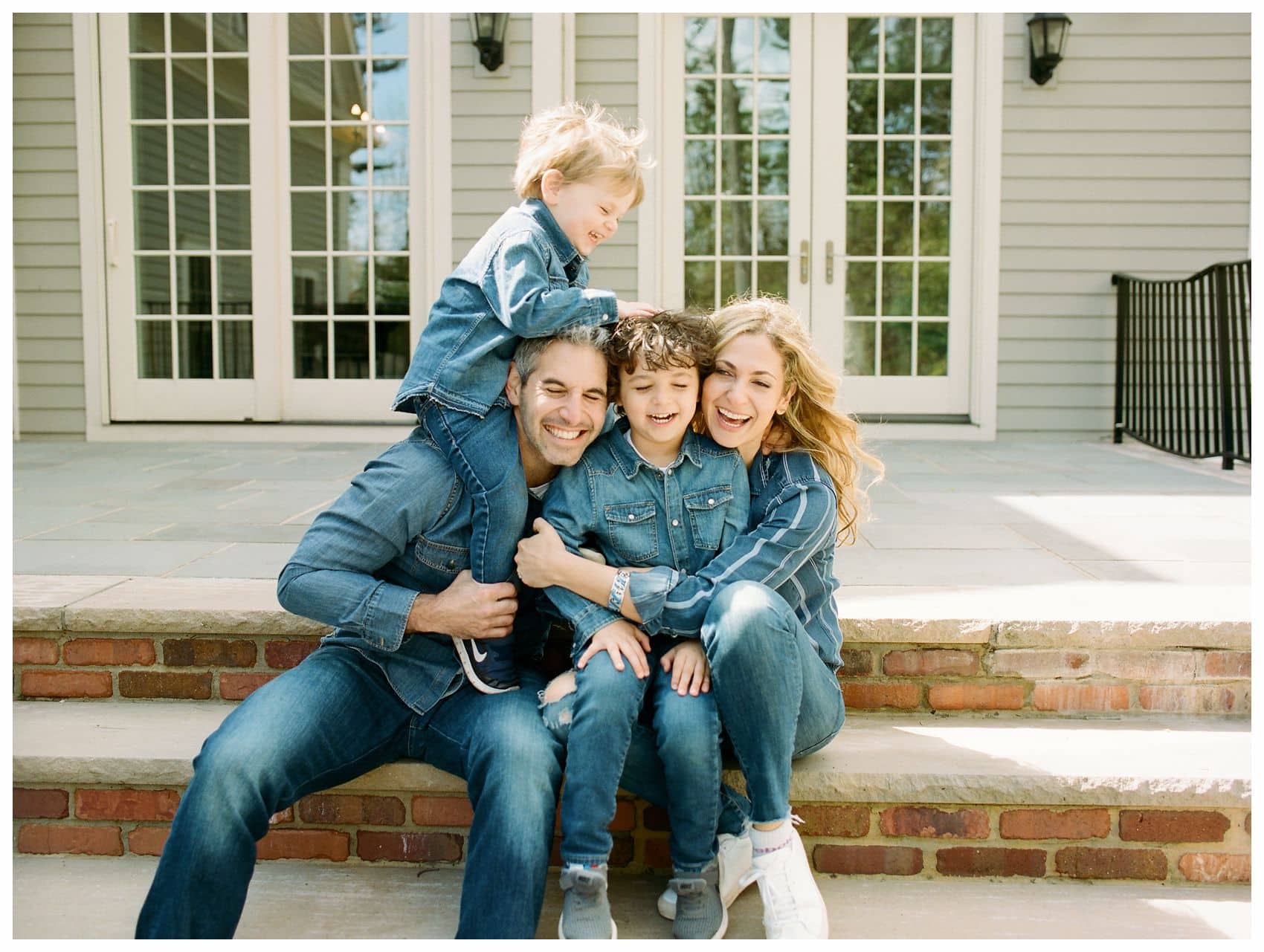 a fun and laughing photo of family with boys sitting on the steps of their home in Montclair NJ