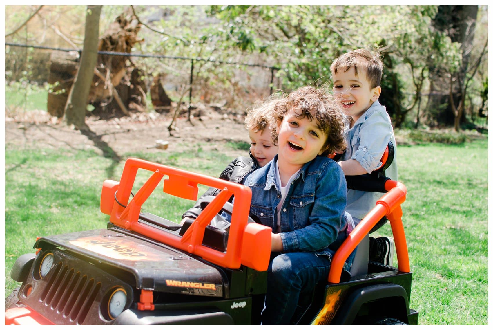 three laughing kids riding a car in their backyard in New Jersey