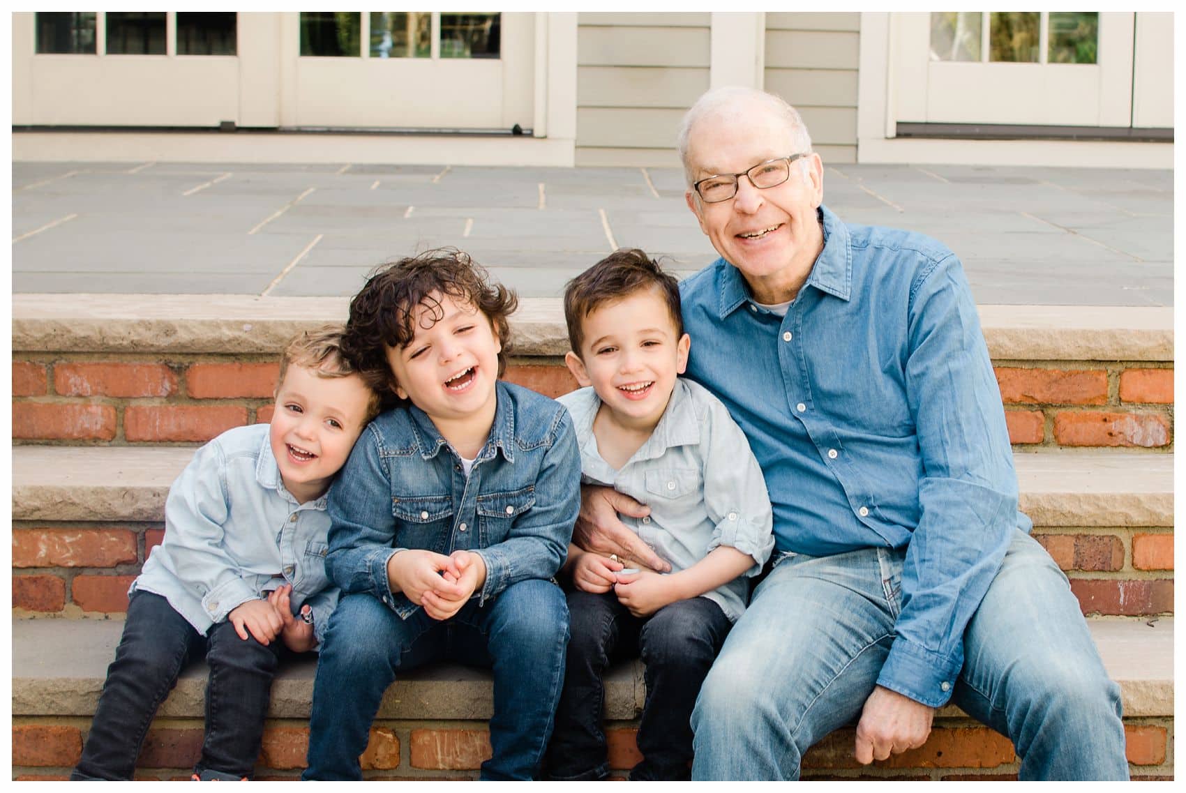 grandfather is laughing and giggling with grandsons on the steps of their home in Montclair NJ for an extended family portrait