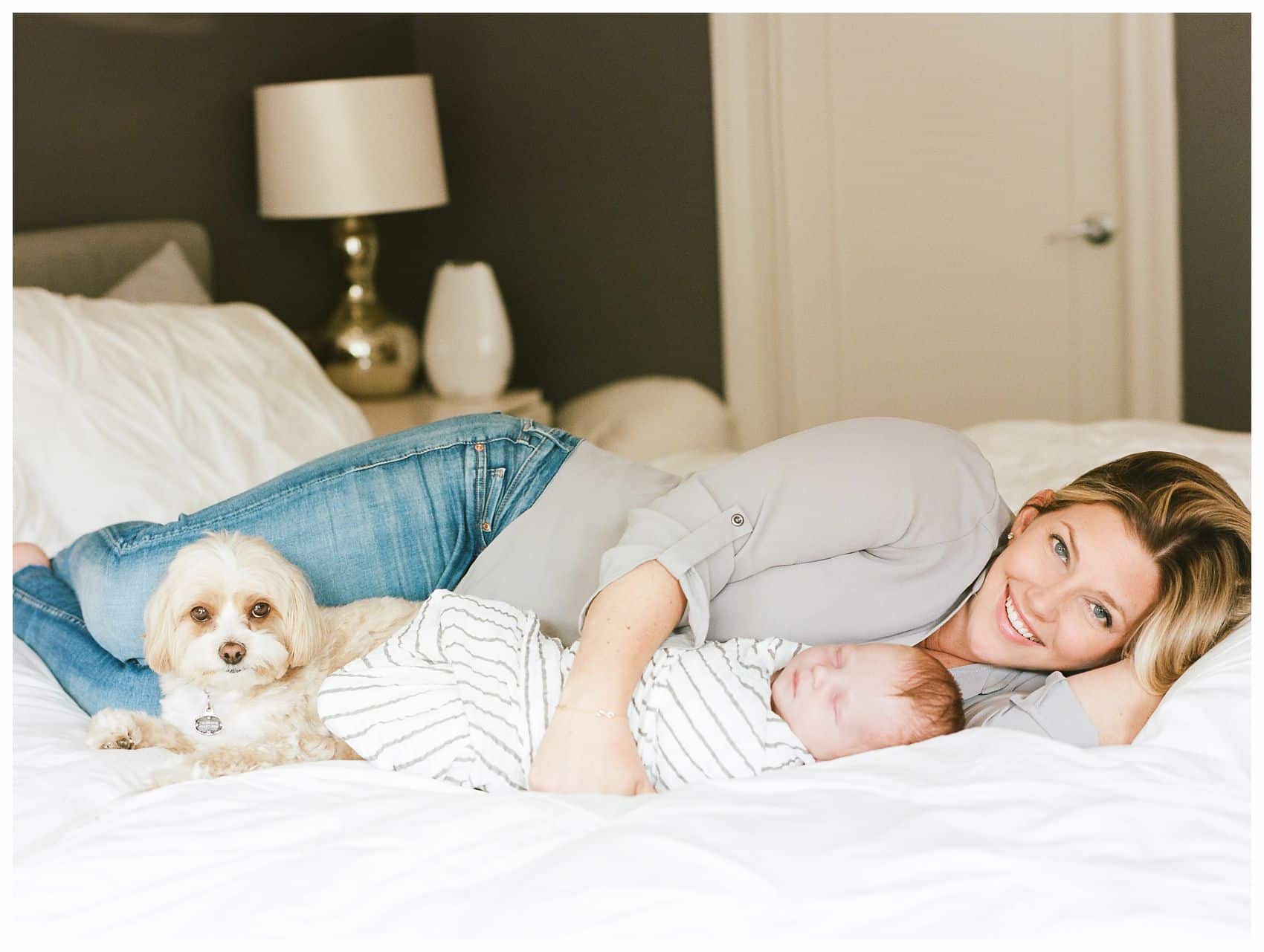 Miriam Dubinsky shares on how to choose the best newborn photographer with lifestyle photo of mom snuggling with baby boy and family dog on bed