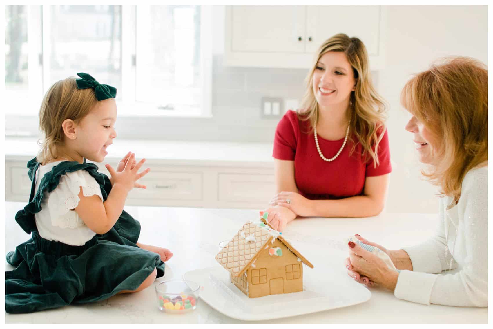 mom daughter and granddaughter building a gingerbread house