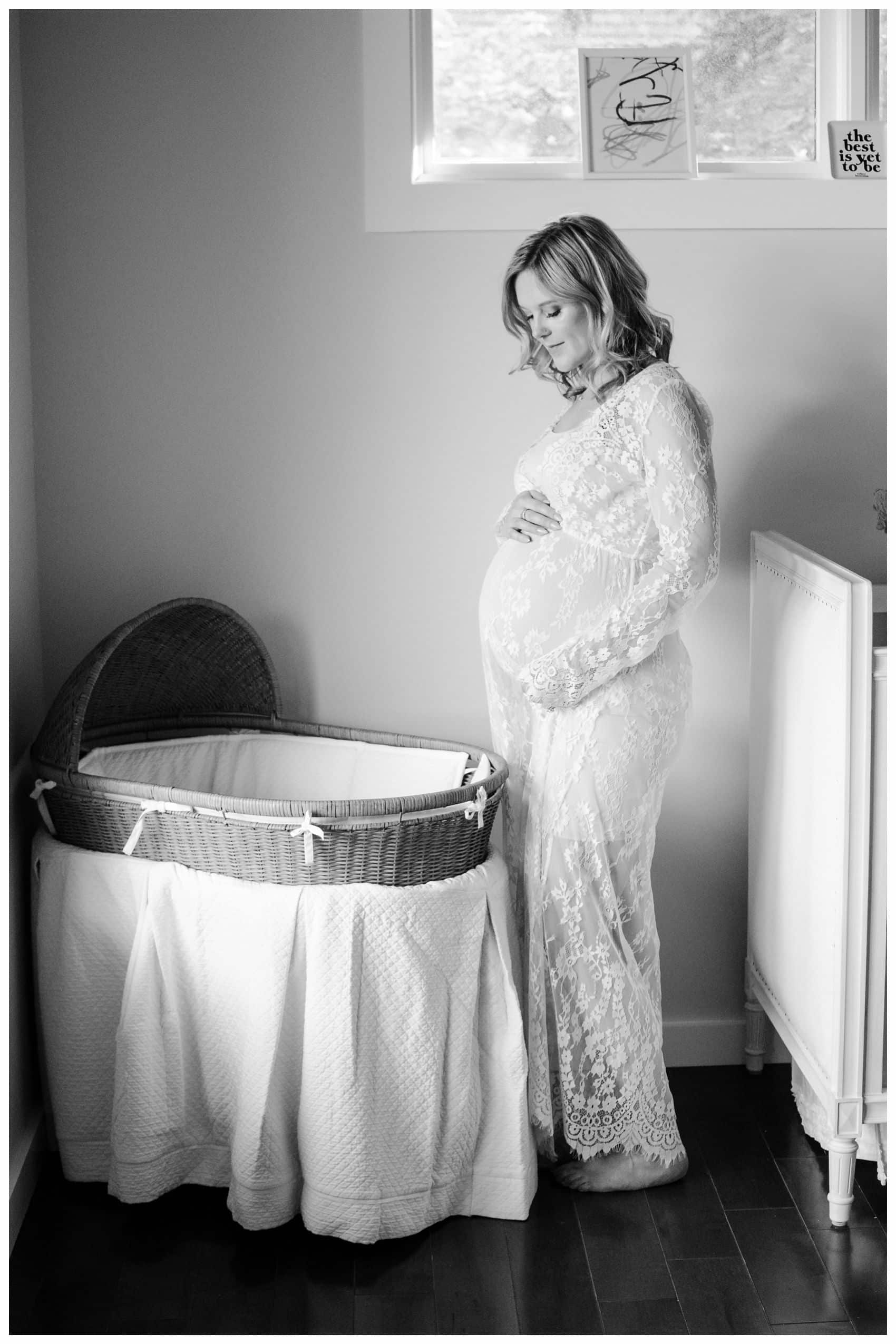 pregnant mom in white lace standing by the crib of her upcoming baby in Essex County NJ
