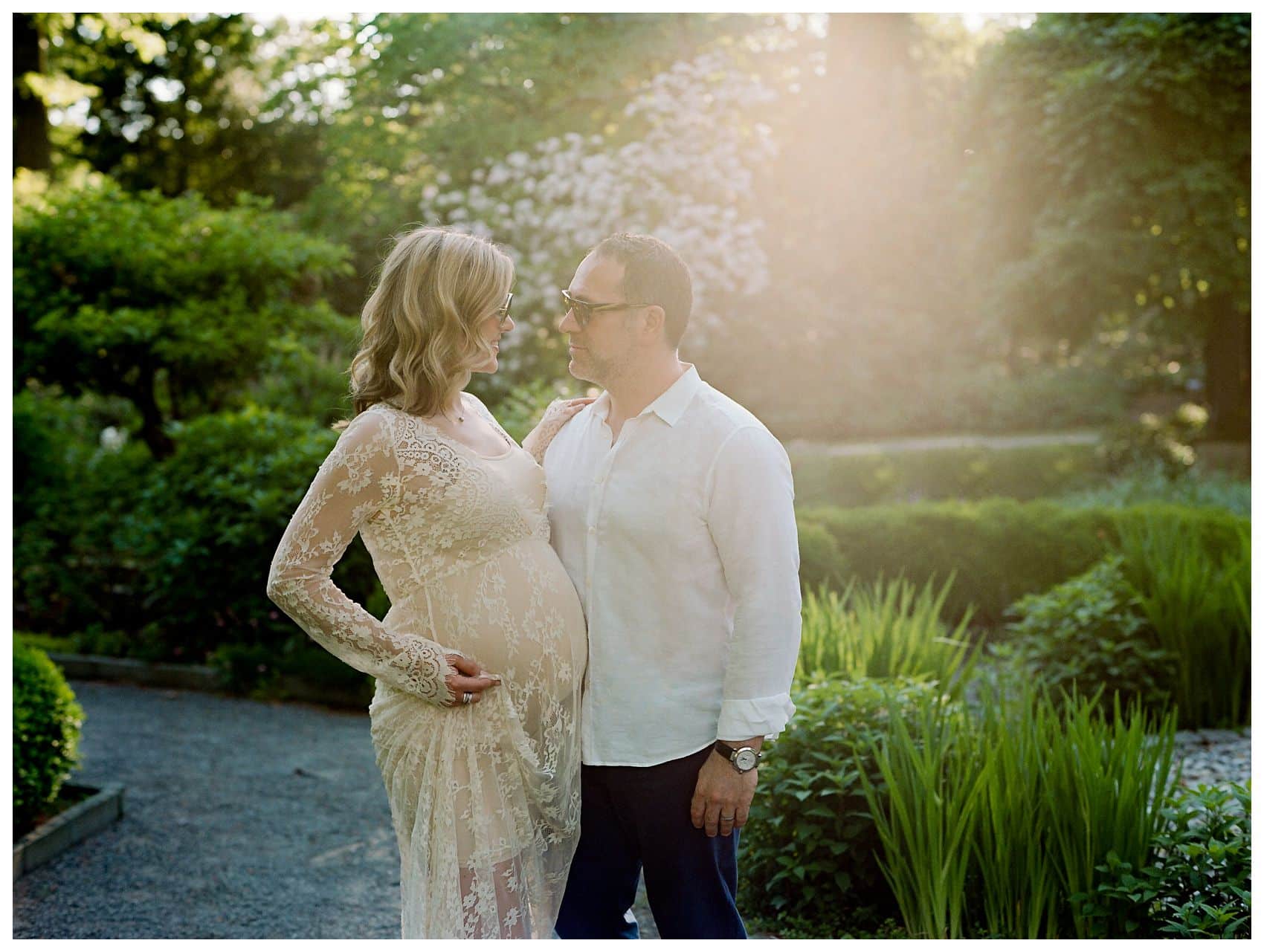 pregnant couple wearing white lace and linen shirt embracing in the maternity session at Van Vleck House & Gardens, Montclair NJ