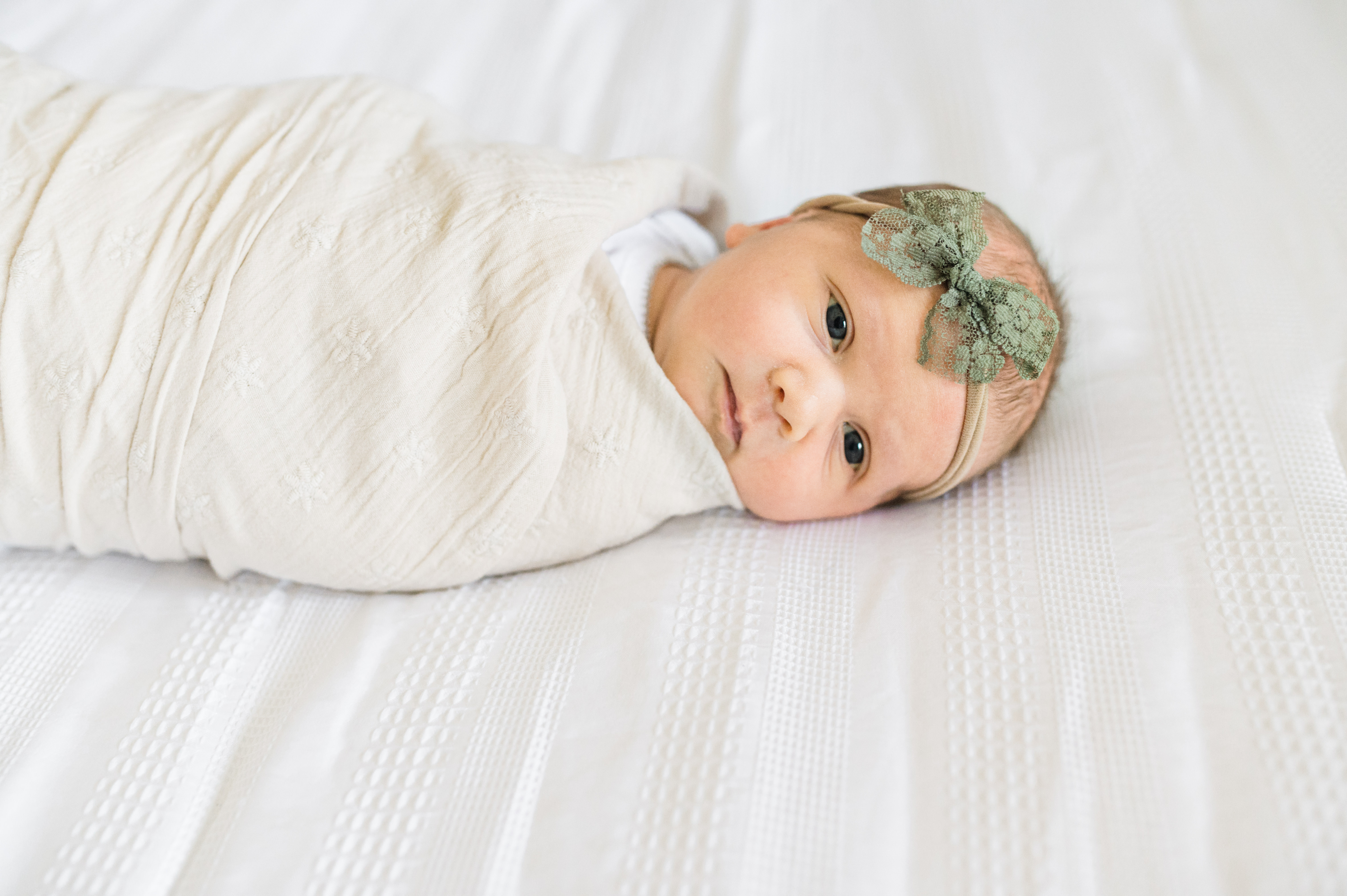 Newborn baby lying wide awake wrapped in a blanket in the newborn photo session with Miriam Dubinsky