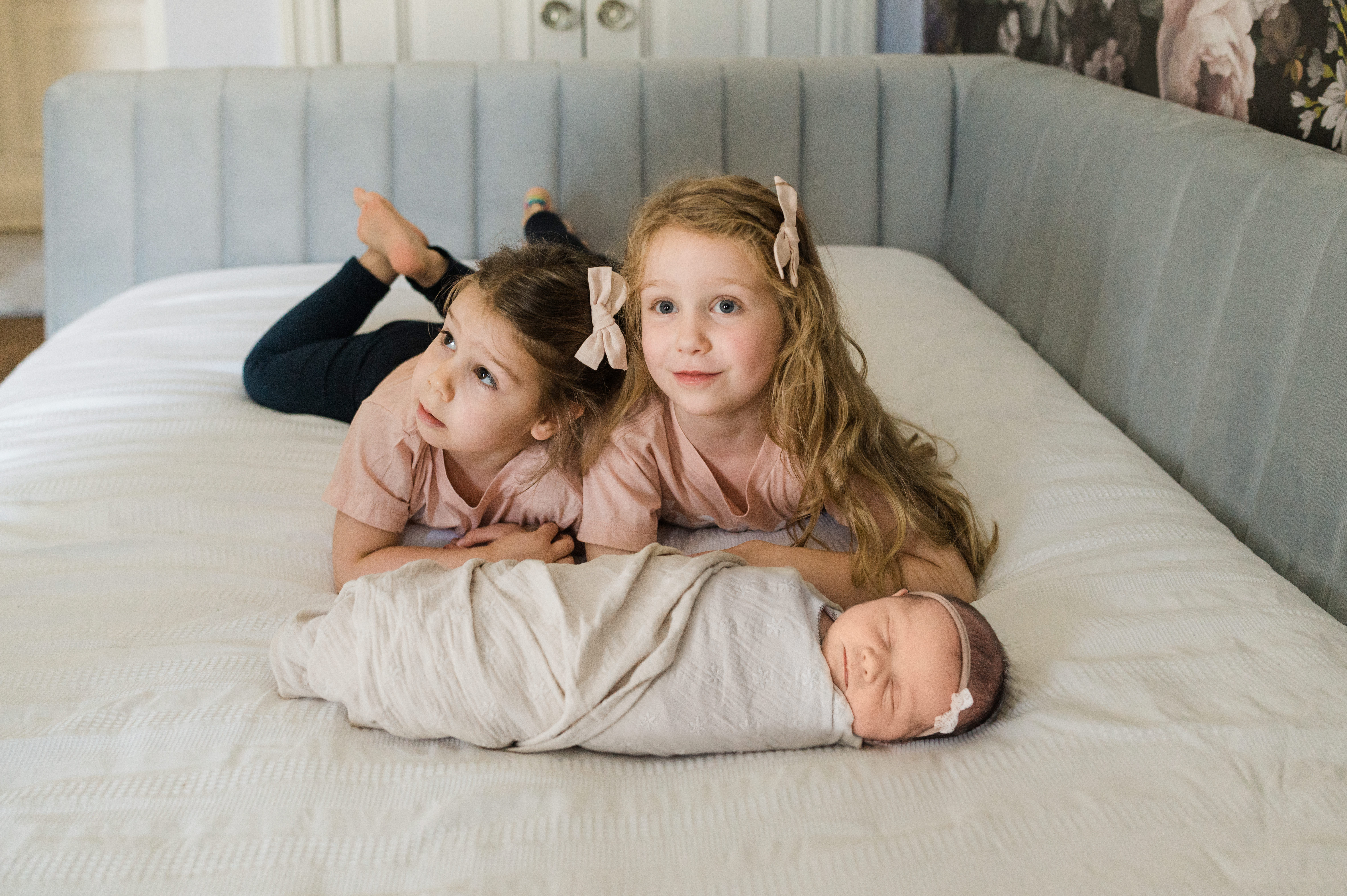 Newborn photography with baby lying on a blanket with two older siblings in NYC home