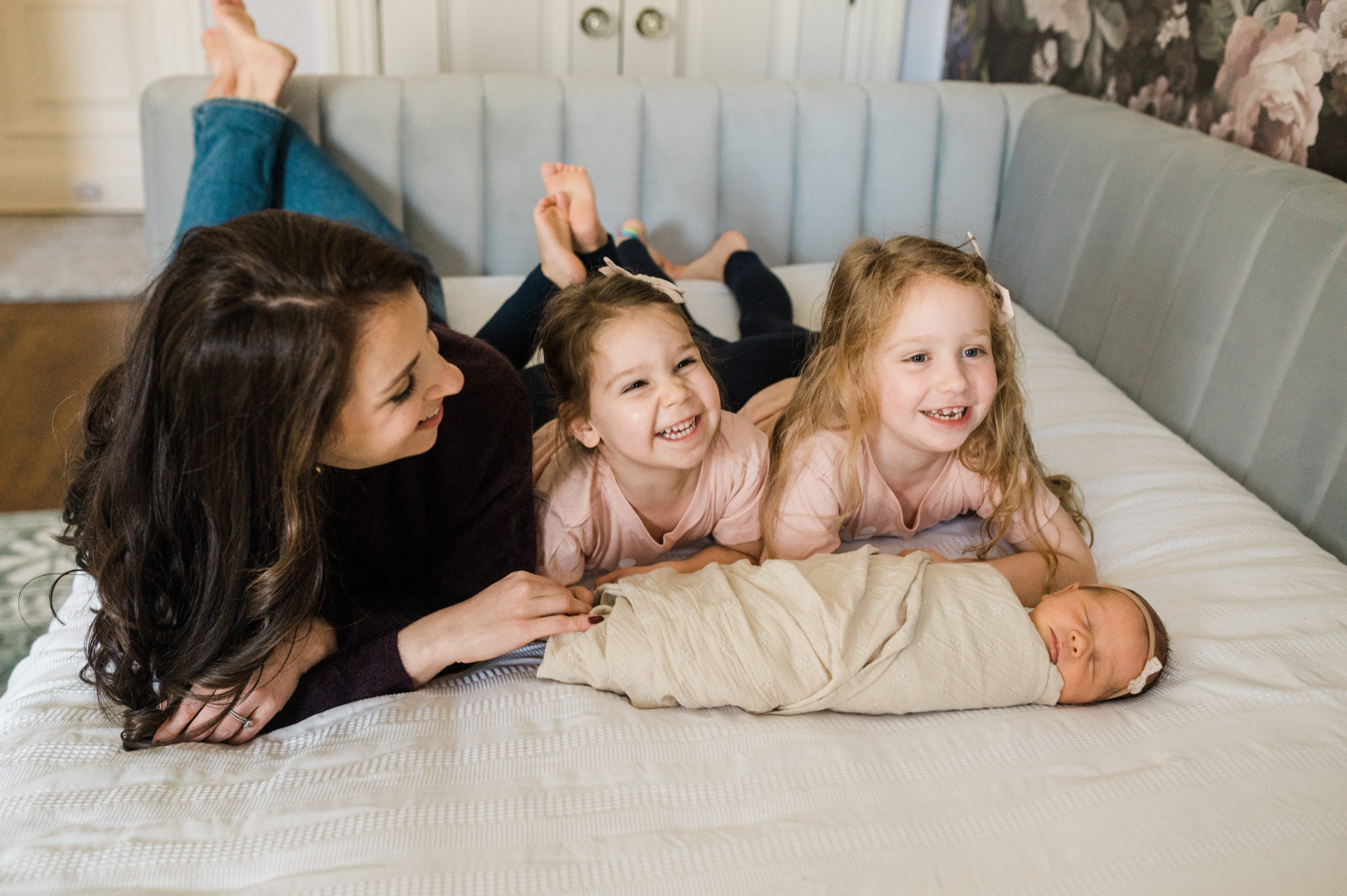 mom and her three girls including her newborn are cuddling on bed in their Manhattan home