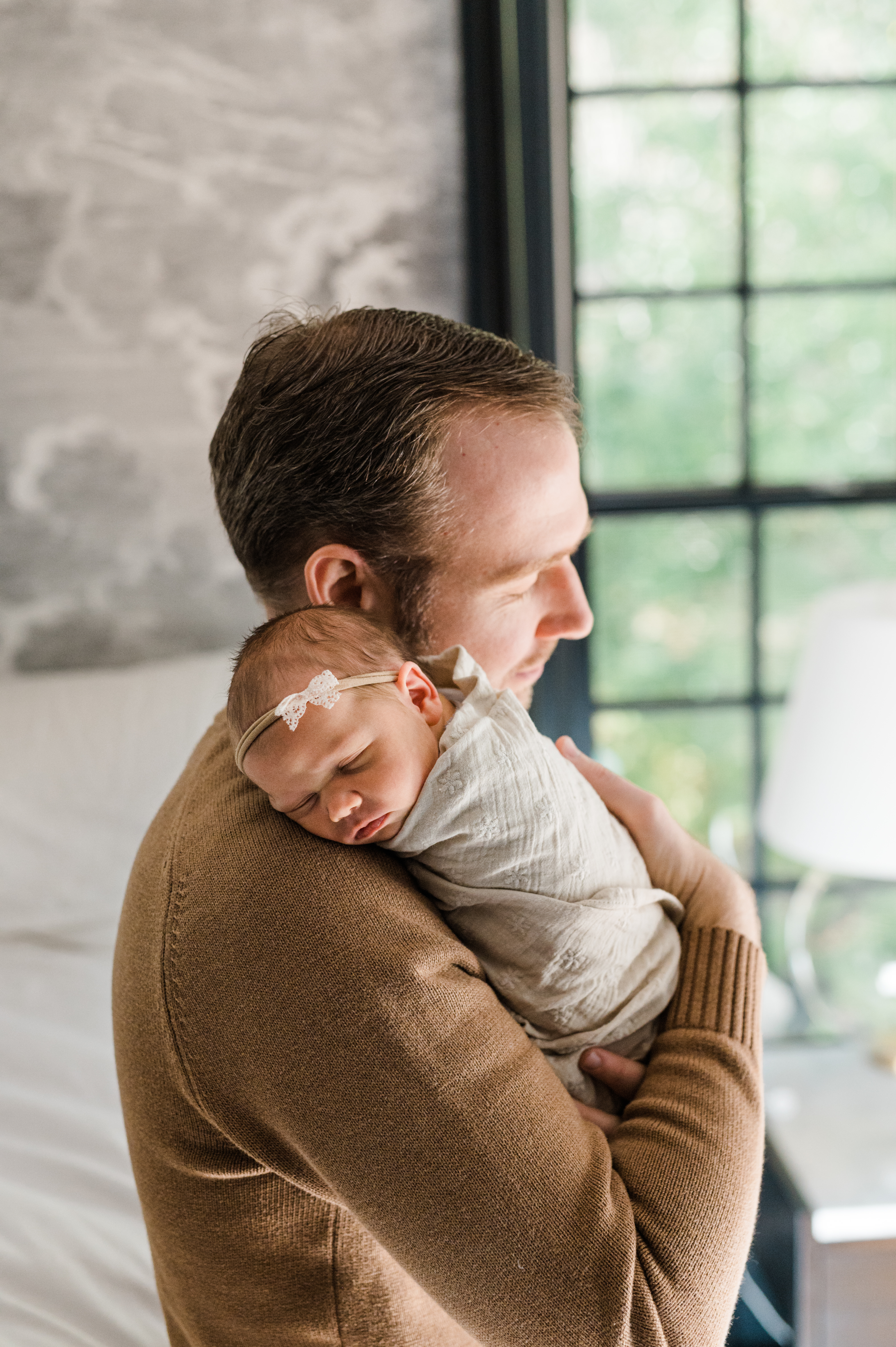 new father is holding gently his new baby girl in their bedroom photographed by Miriam Dubinsky Photography